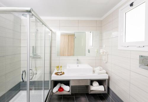 a white bathroom with a sink and a shower at Eurovillage Achilleas Hotel in Mastichari