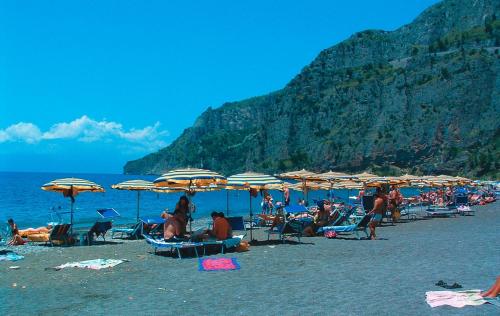 a group of people sitting on a beach with umbrellas at Hotel Club San Diego in Maratea