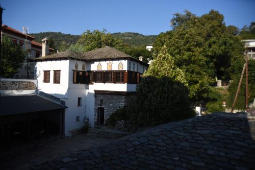 a white house with a roof on a stone street at Archontiko Klitsa in Portariá