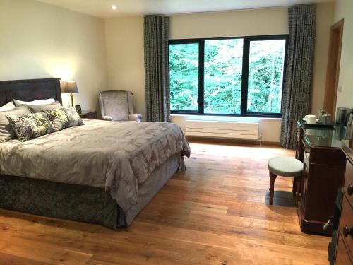 um quarto com uma cama, uma cadeira e janelas em White Lodge B&B em Cooksbridge