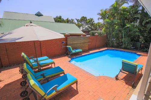 uma piscina com duas espreguiçadeiras e um guarda-sol em Mount Edgecombe Estate Lodge em Mount Edgecombe