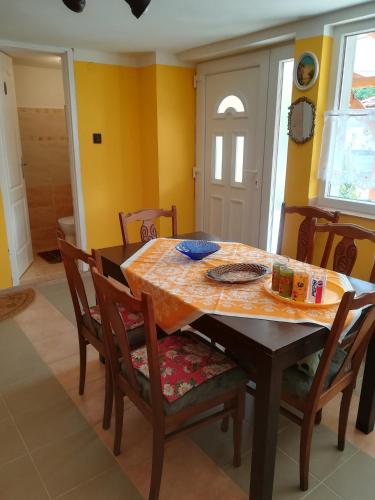 a dining room table and chairs with yellow walls at Nagymama Házikója in Tiszasas