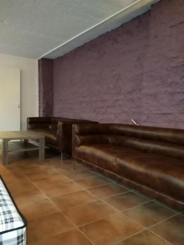 a living room with brown leather furniture and a red wall at Hostel31 in Tallinn