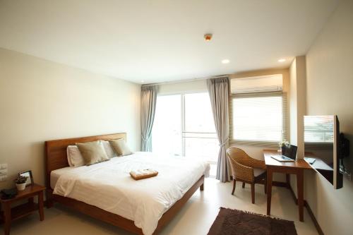 a bedroom with a bed and a desk and a television at Nivas Chiangmai in Chiang Mai
