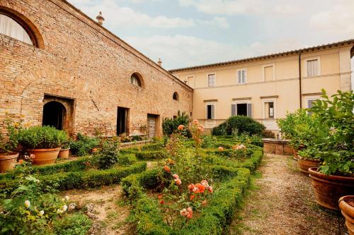 un jardín con flores y plantas frente a un edificio en Agriturismo Borgo Villa Certano, en Siena