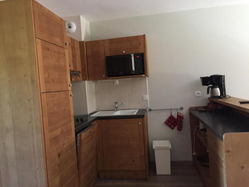 a small kitchen with wooden cabinets and a sink at Duplex Familial à Vars, Chalets des Rennes in Vars