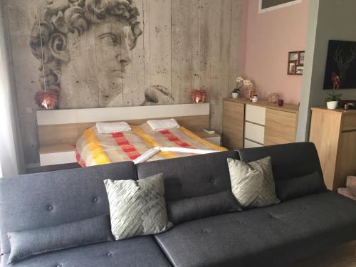 ein Wohnzimmer mit einem Sofa vor einem Bett in der Unterkunft Hunyadi Apartman in Szekszárd