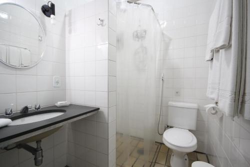 a bathroom with a toilet and a sink and a mirror at Mira Maré Praia Hotel in Guarujá