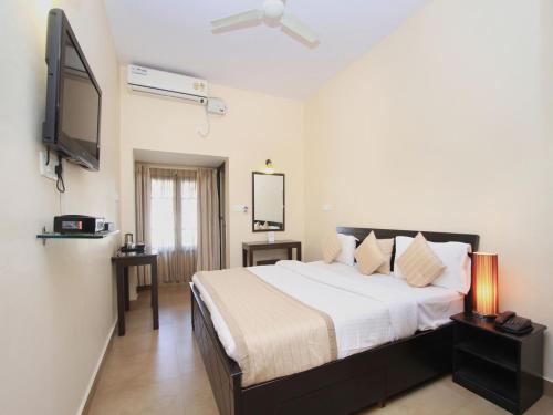 a bedroom with a bed and a flat screen tv at Bota Royal in Kushālnagar