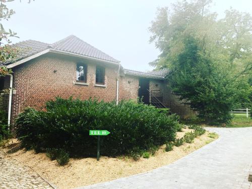 a house with a green sign in front of it at Gîtes du Golf in Sart-Dames-Avelines