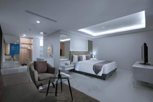 a bedroom with a bed and a living room at Hotel Neo Gajah Mada Pontianak by ASTON in Pontianak