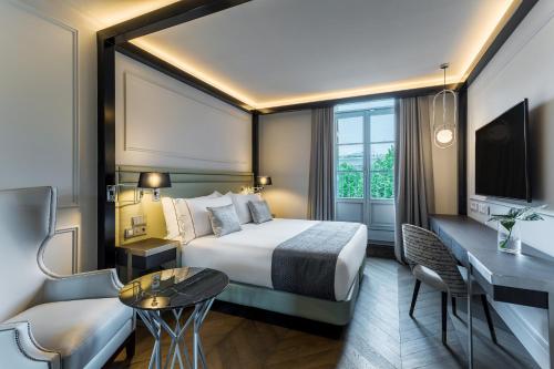 サン・セバスティアンにあるRoom Mate Gorkaのベッドとデスクが備わるホテルルームです。