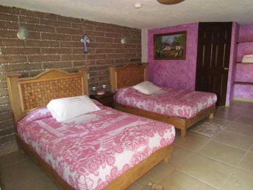 a bedroom with two beds and a brick wall at Hotel y Cabañas una Cosita de Zacatlán in Zacatlán