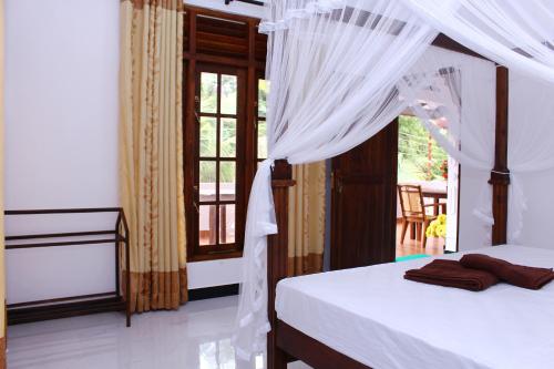 a bedroom with a bed with a canopy and a window at Amal Guest house in Mirissa