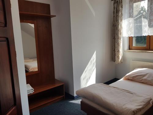 Dormitorio pequeño con cama y espejo en Białe Wzgórze, en Okonek