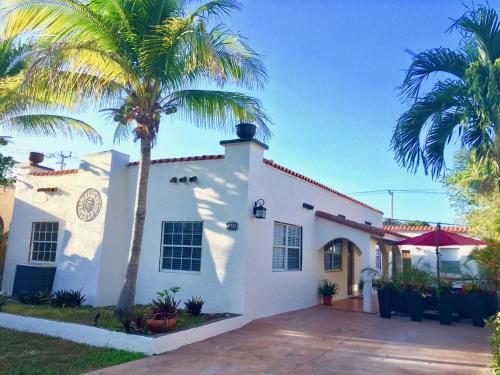 a white house with palm trees in front of it at A Suite Retreat in Miami