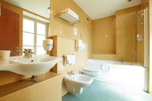 a bathroom with a sink and a toilet and a tub at Liberty Hotel in Turin