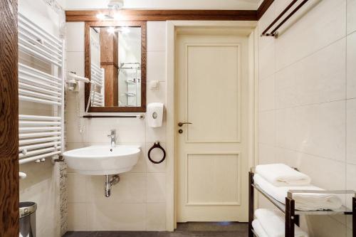 a white bathroom with a sink and a mirror at Elegant Apartments in Krakow