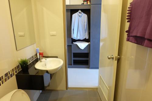 a bathroom with a sink and a shirt in a closet at Trio Residence Si-Racha in Si Racha