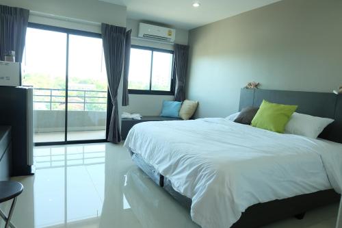 a bedroom with a large bed and a balcony at Trio Residence Si-Racha in Si Racha