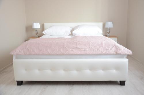 ビャウィストクにあるMulti Apartment Łąkowa 18/13の白いベッド(ピンクの掛け布団、ランプ2つ付)