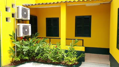 a yellow building with black windows and plants at Residencialdes in São Tomé