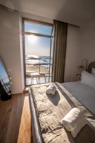 une chambre avec un lit et une vue sur l'océan dans l'établissement Pavillon de la plage, à Trébeurden