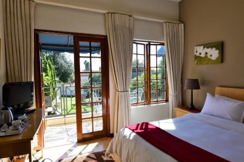 1 dormitorio con 1 cama y puerta corredera de cristal en Highgrove Guesthouse, en Johannesburgo