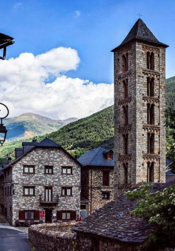 an old stone building with a tower and a mountain at Hostal La Plaça in Erill la Vall