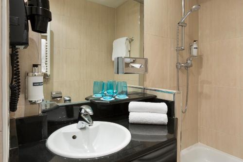 La salle de bains est pourvue d'un lavabo et d'une douche. dans l'établissement Hotel Paris Opera Affiliated by Meliá, à Paris