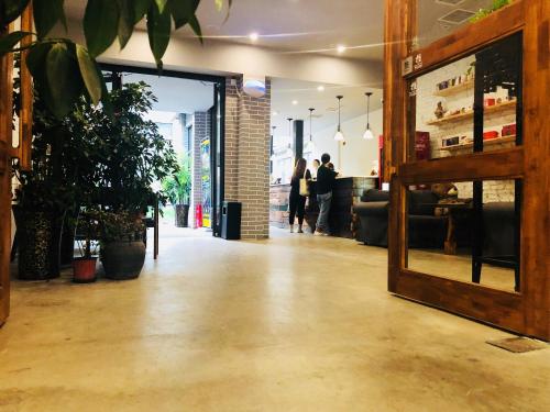 a room with people standing in the background and a lobby at 洛阳一见客栈 in Luoyang