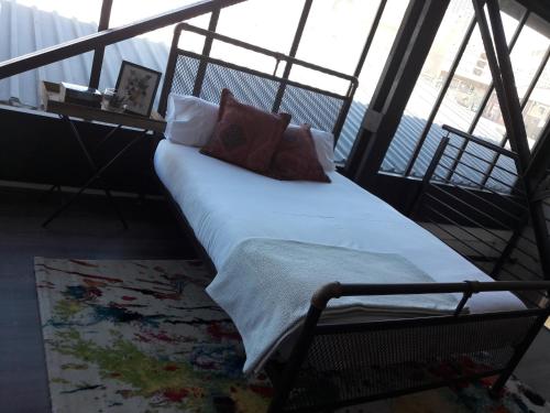 1 cama con almohadas en una habitación con ventanas en Entire Industrial-Style Loft in Maboneng, en Johannesburgo