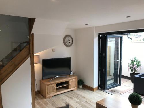 a living room with a television and a clock on the wall at No 4 Elizabeth Street in Congleton