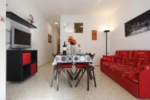 ベナルマデナにあるBonito apartamento con barbacoaのリビングルーム(テーブル、赤いソファ付)