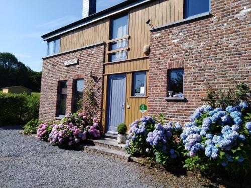 a brick house with flowers in front of it at Gîte Wellness "Le Poirier" in Durbuy