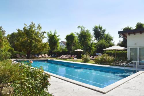 a pool with chairs and umbrellas next to a building at Hotel Hirschen in Freiburg-Lehen in Freiburg im Breisgau