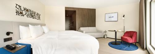 a hotel room with a large bed and a red chair at Radisson Blu Hotel, Bruges in Bruges