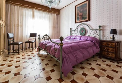 Pratola PelignaにあるLa Villaのベッドルーム(紫色のベッド1台、椅子付)