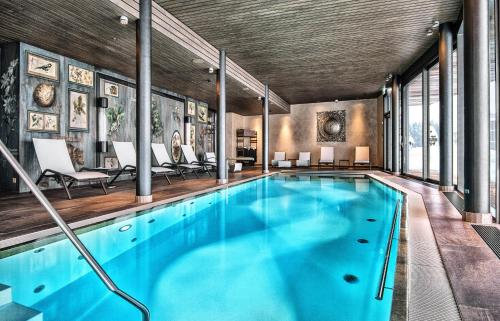 an indoor pool with blue water in a house at Valsana Hotel Arosa in Arosa