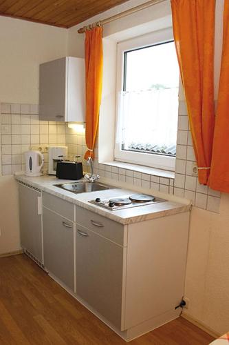 a kitchen with a sink and a window with orange curtains at Haus Barbara in Bad Füssing