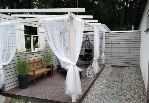 a white pergola with a bench on a patio at Pokoje, apartament NA WYSPIE in Gdańsk