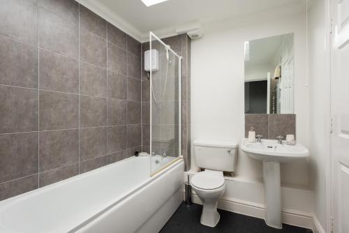 a bathroom with a toilet and a sink and a bath tub at The Old Station House - Stylish & Central 2BDR Apartment in Oxford