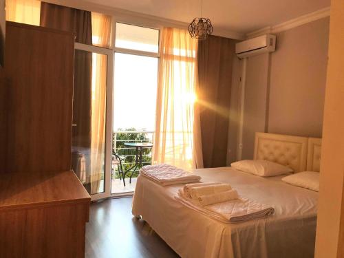 a bedroom with a bed and a window with a balcony at Albatross Kvariati Guest House in Kvariati