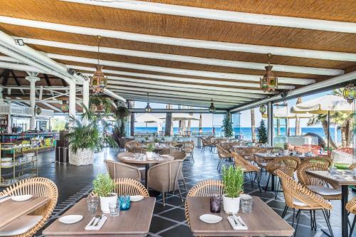 エステポナにあるBahía Beach Apartments Esteponaの木製の天井、テーブルと椅子のあるレストラン