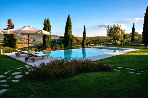 a swimming pool with an umbrella and a bench next to it at Poggio ai Gelsi in Pienza