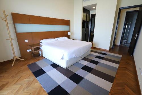 a bedroom with a white bed and a checkered floor at The Straits Quay Marina by Messina Clive in George Town