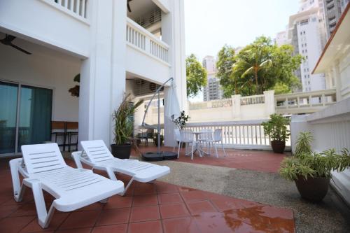 a balcony with two white chairs and a table at The Straits Quay Marina by Messina Clive in George Town