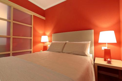 a bedroom with orange walls and a bed with two lamps at Agriturismo Tenuta "Il Cigno" in Villanterio