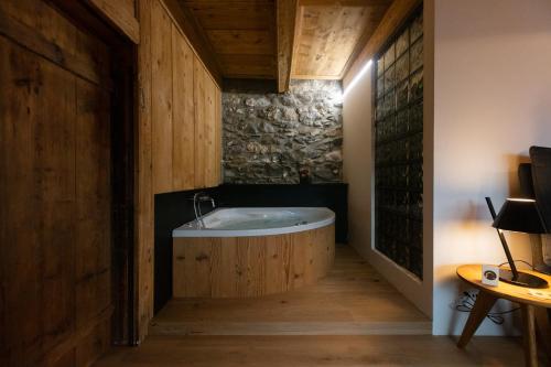 een badkamer met een bad in een kamer met houten wanden bij La Grande Maison in Savièse