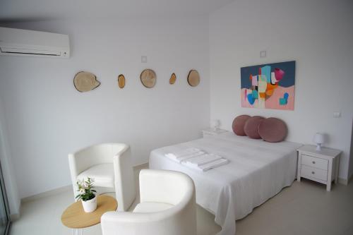 a white bedroom with a white bed and a chair at Apartamentos Pinhão in Lagos